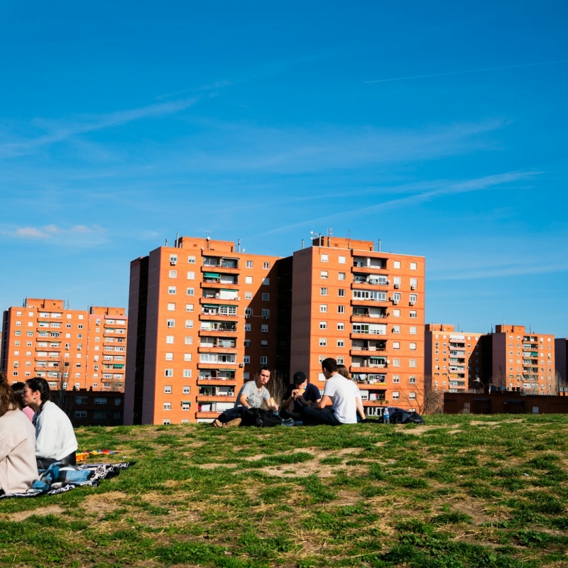 man in white shirt sitting on green grass field near city buildings during daytime